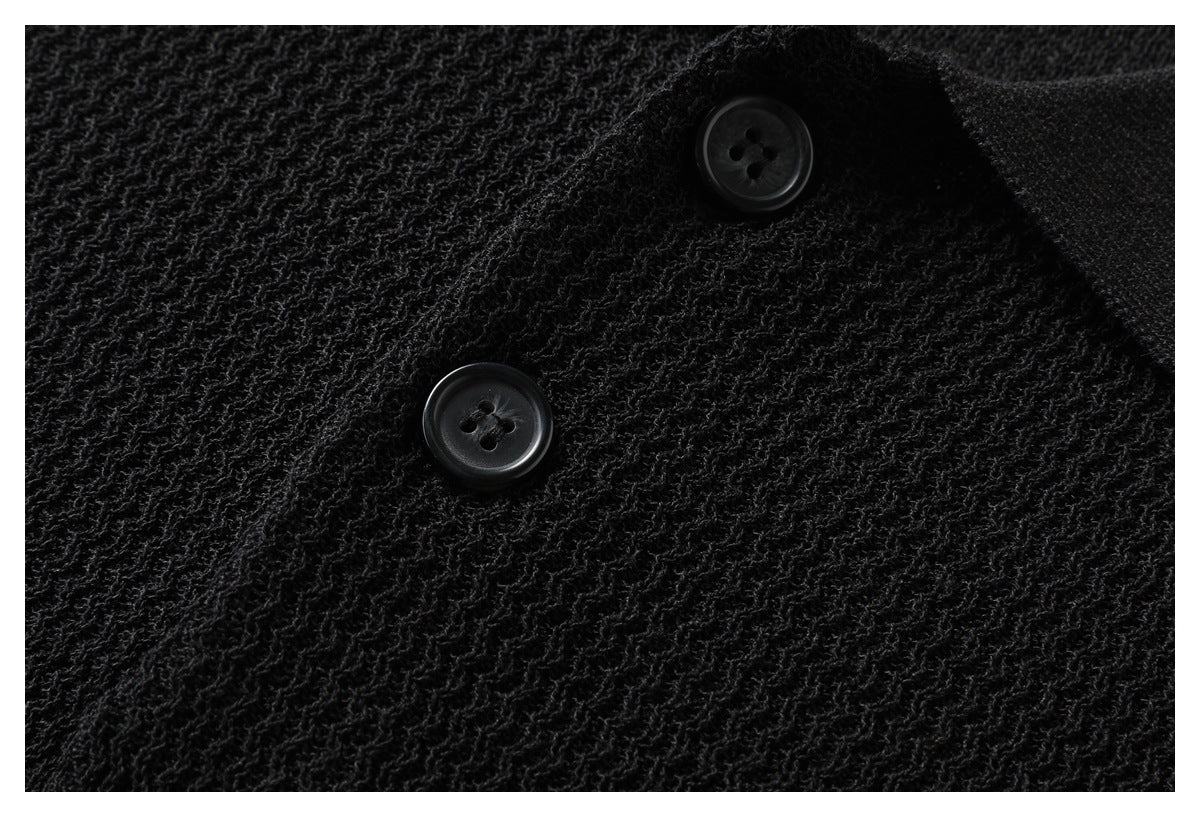 Close-up of the black polo's textured knit and two black buttons on the front placket.