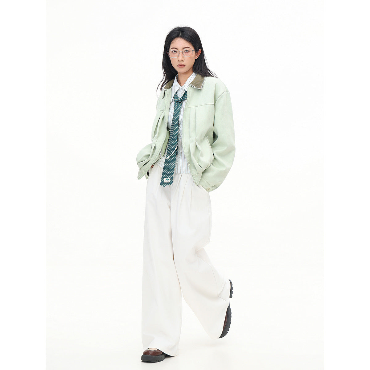 Full-length model wearing a pale mint zip jacket with a contrasting collar, white wide-leg trousers, striped shirt and tie.