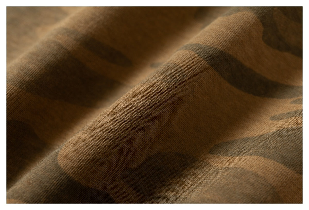Close-up of brown camouflage fabric draped in folds, showing its surface texture.
