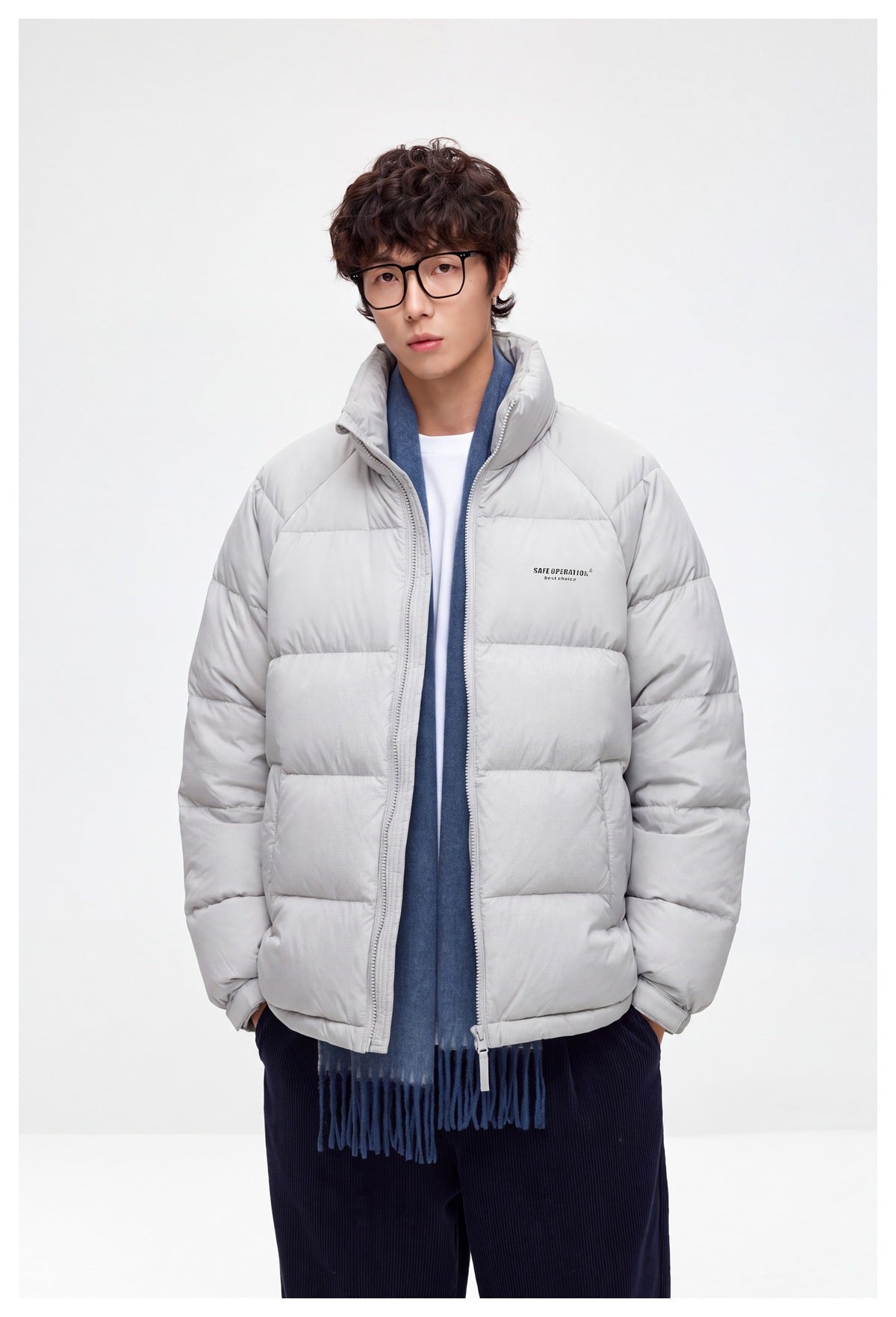 Front view of a model wearing a light gray quilted puffer jacket with a high collar and blue scarf.