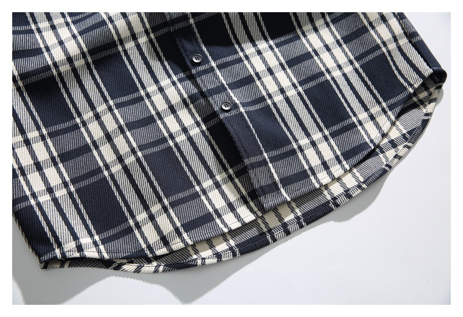 Close-up of a navy, black, and cream plaid shirt hem with two dark buttons.