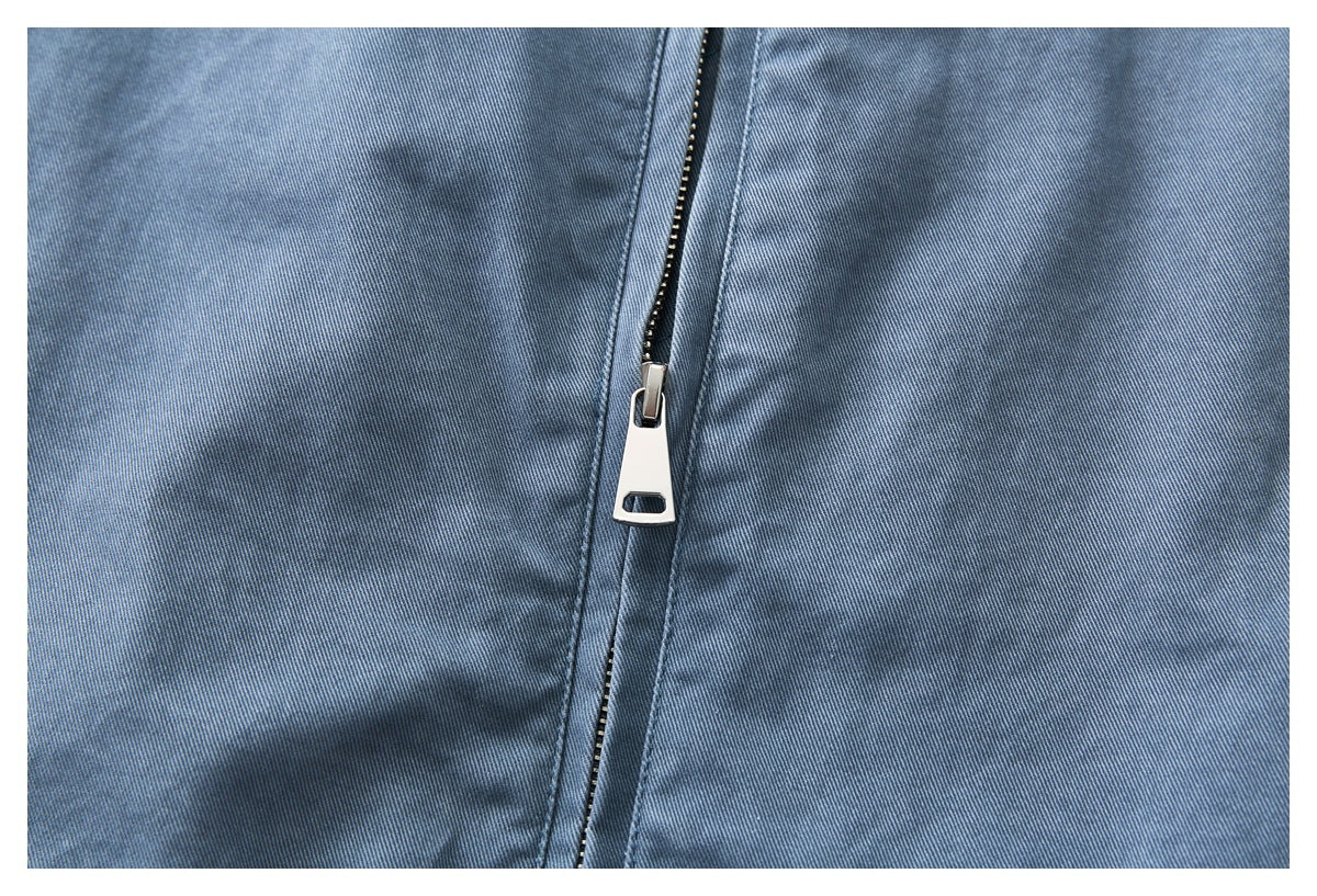 Close-up of a silver zipper on blue garment fabric.