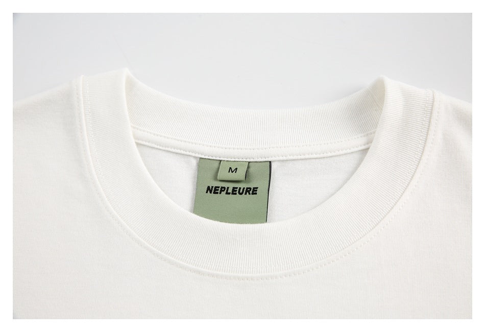 Close-up of a white T-shirt's ribbed crew neck and green NEPLEURE size M label.