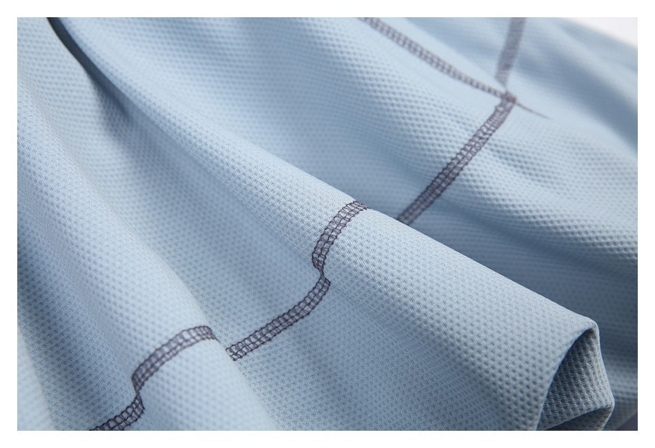 Macro view of light blue textured fabric with curved dark overlock seams.