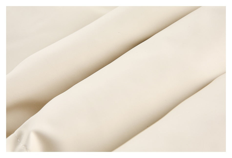 Close-up of smooth cream fabric arranged in soft diagonal folds.