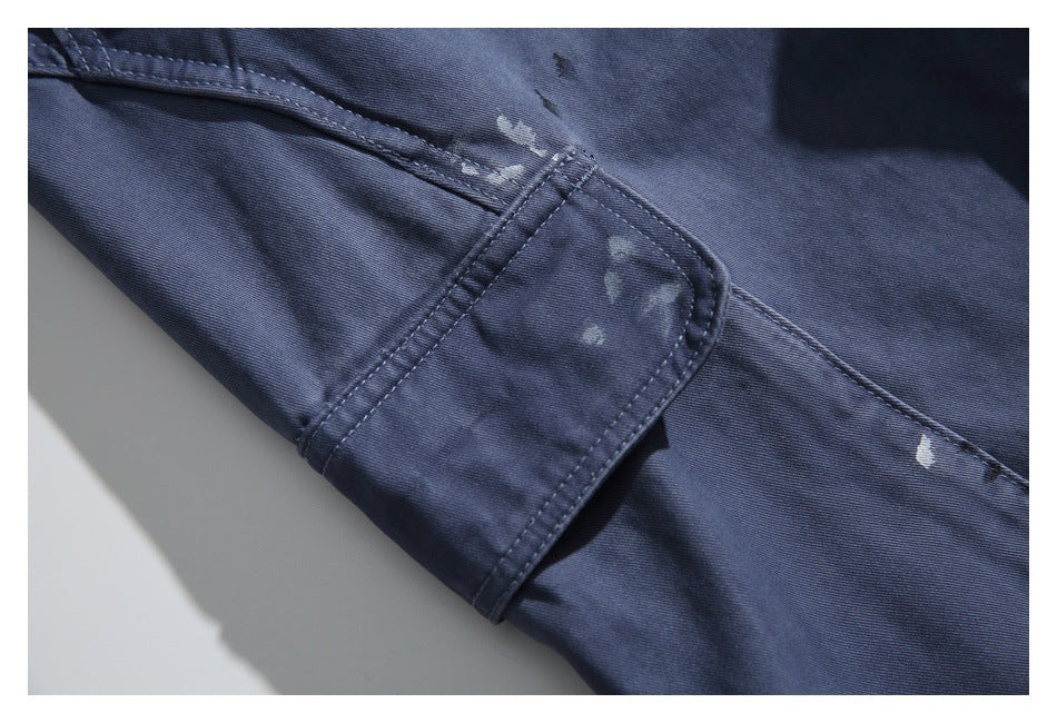 Close-up of navy garment fabric with a stitched tab, seams and scattered pale distressed marks.