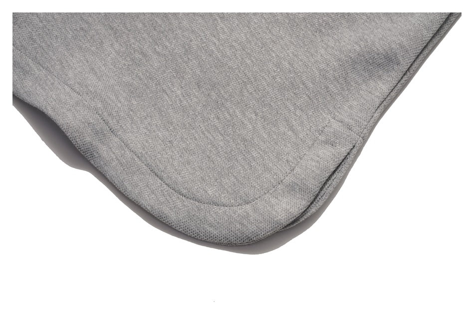 Close-up of light gray knit fabric showing a curved stitched seam and finished edge.