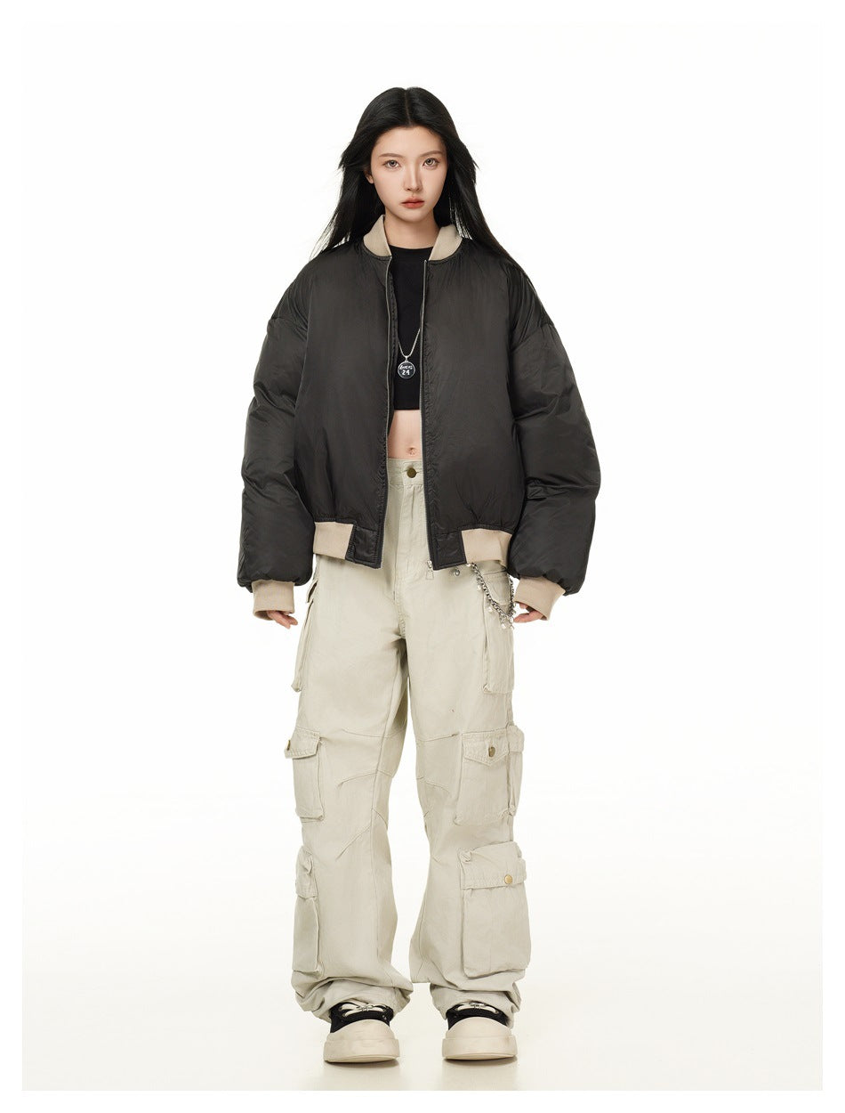Full-length model wearing a black oversized bomber jacket with beige ribbed trim and light-colored cargo pants.