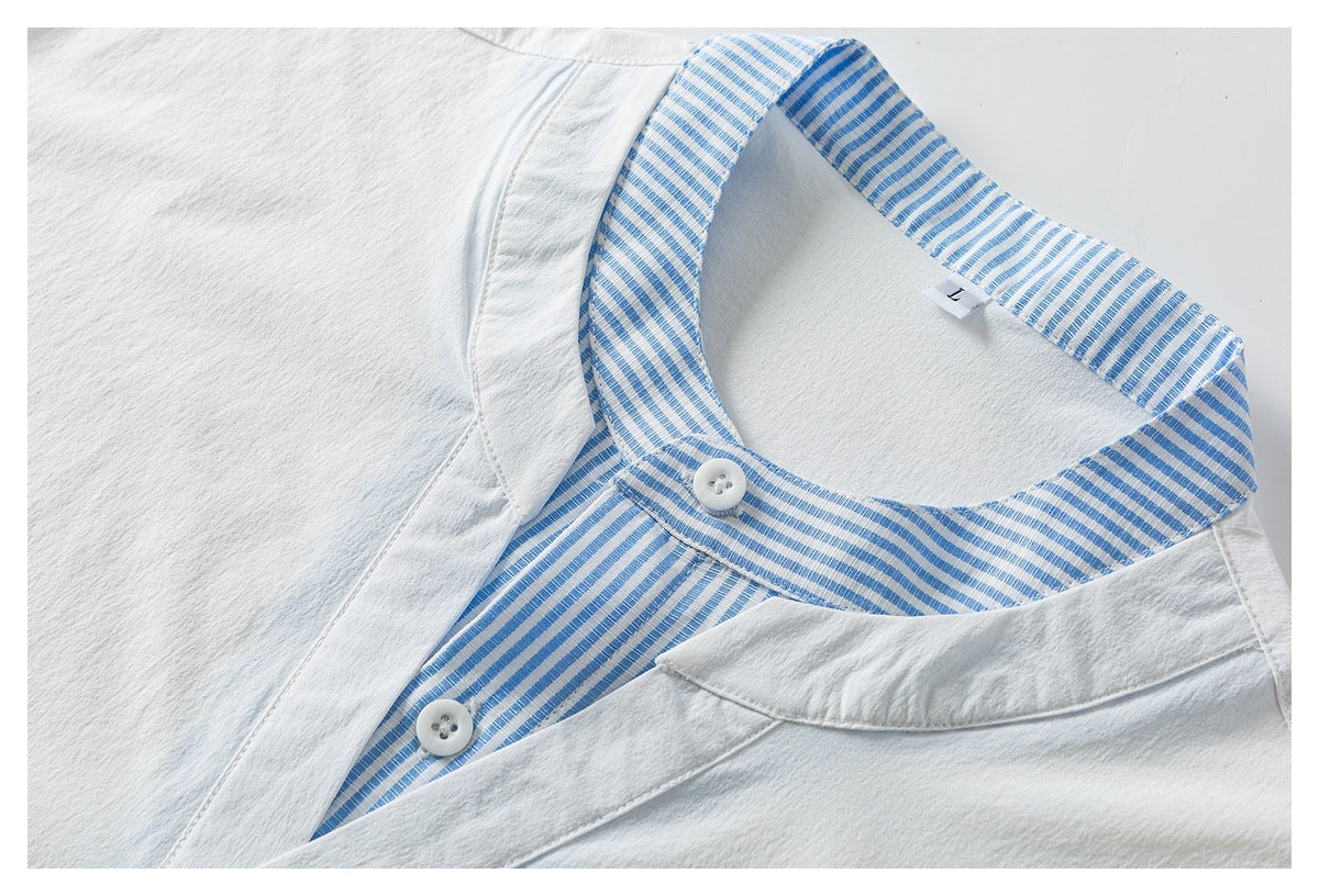 Close-up of white shirt neckline with blue-and-white striped inner collar, two white buttons and V-shaped placket