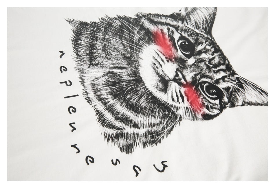 Close-up of a black-and-white cat graphic with red accents and stylized lettering on white fabric.