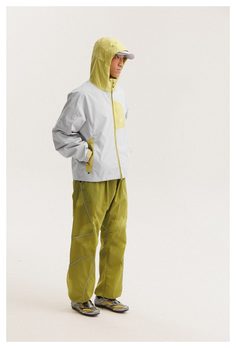 Model in a light gray hooded jacket with chartreuse accents and matching chartreuse pants, shown in profile.