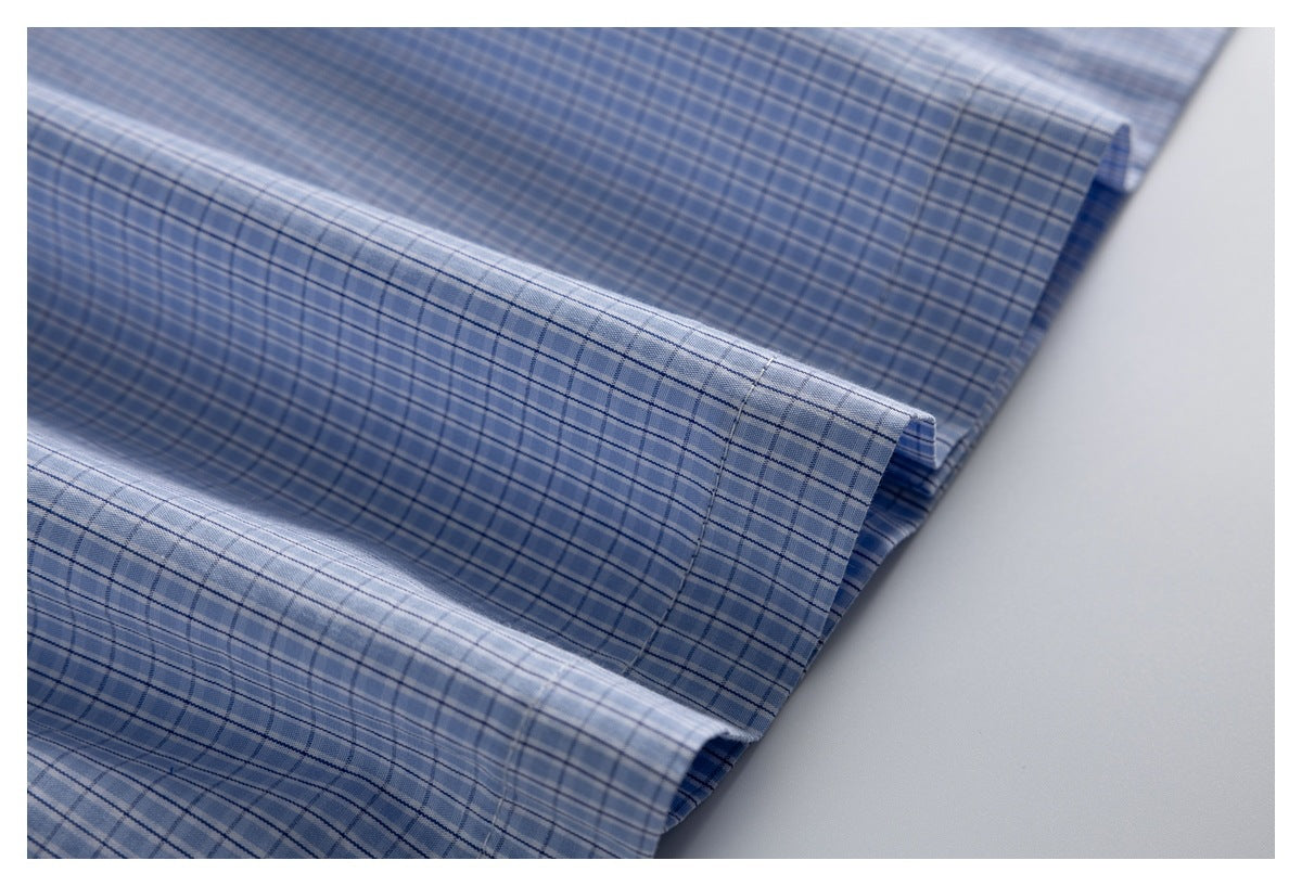 Close-up of folded edges and stitching on a blue-and-white check shirt.