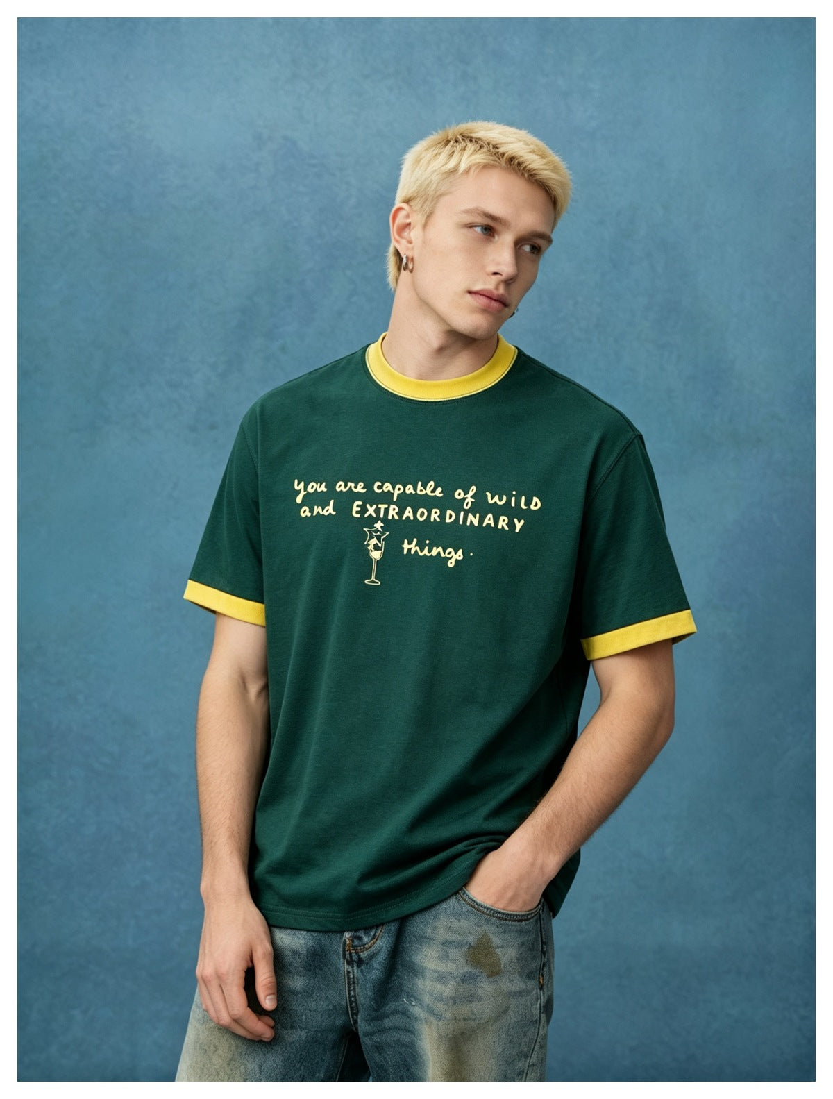 Model wearing a dark green T-shirt with yellow collar and sleeve trim and a yellow slogan graphic.