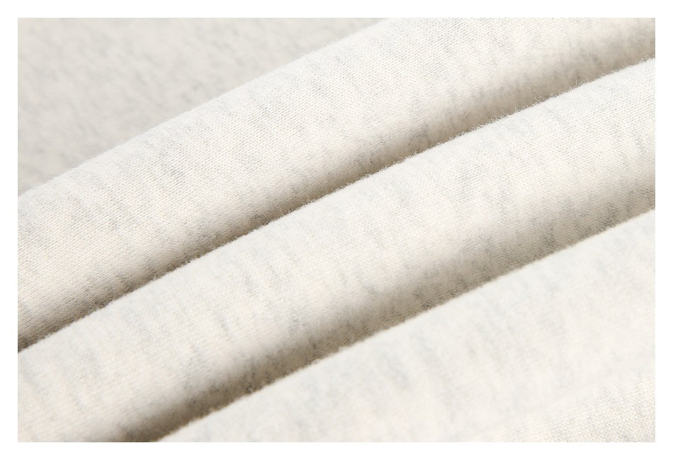Close-up of folded ivory heather sweatshirt fabric showing its surface texture.