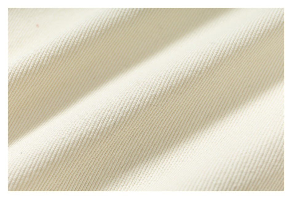 Extreme close-up showing the diagonal ribbed texture of ivory fabric.