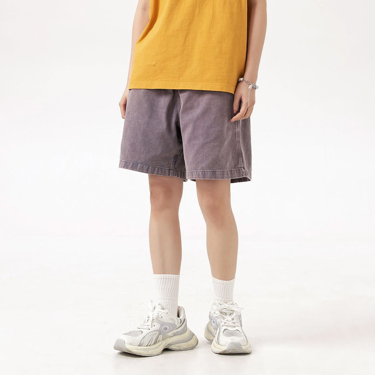 Front view of a model wearing loose, muted mauve drawstring shorts.