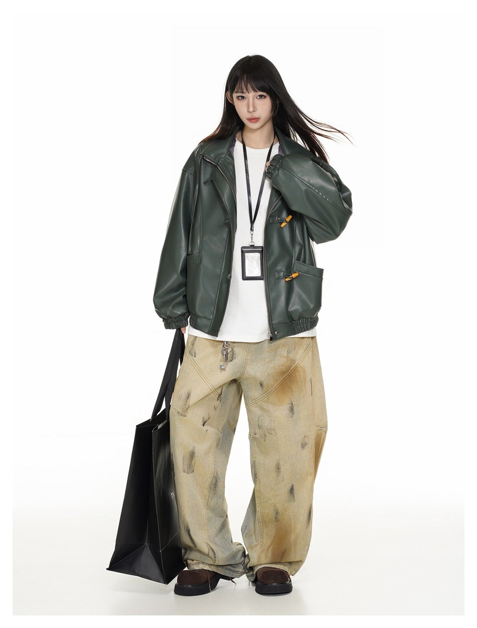 Model in a dark green faux-leather jacket with toggle details over a white tee, wide-leg pants and a black tote bag