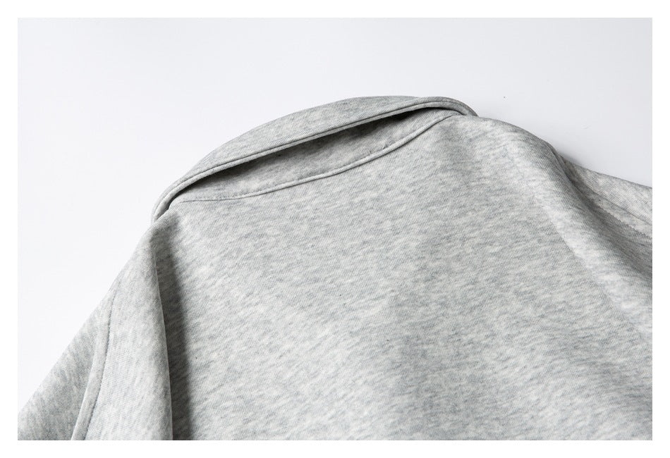Close-up of the back neckline and shoulder seam on a light gray heather garment.