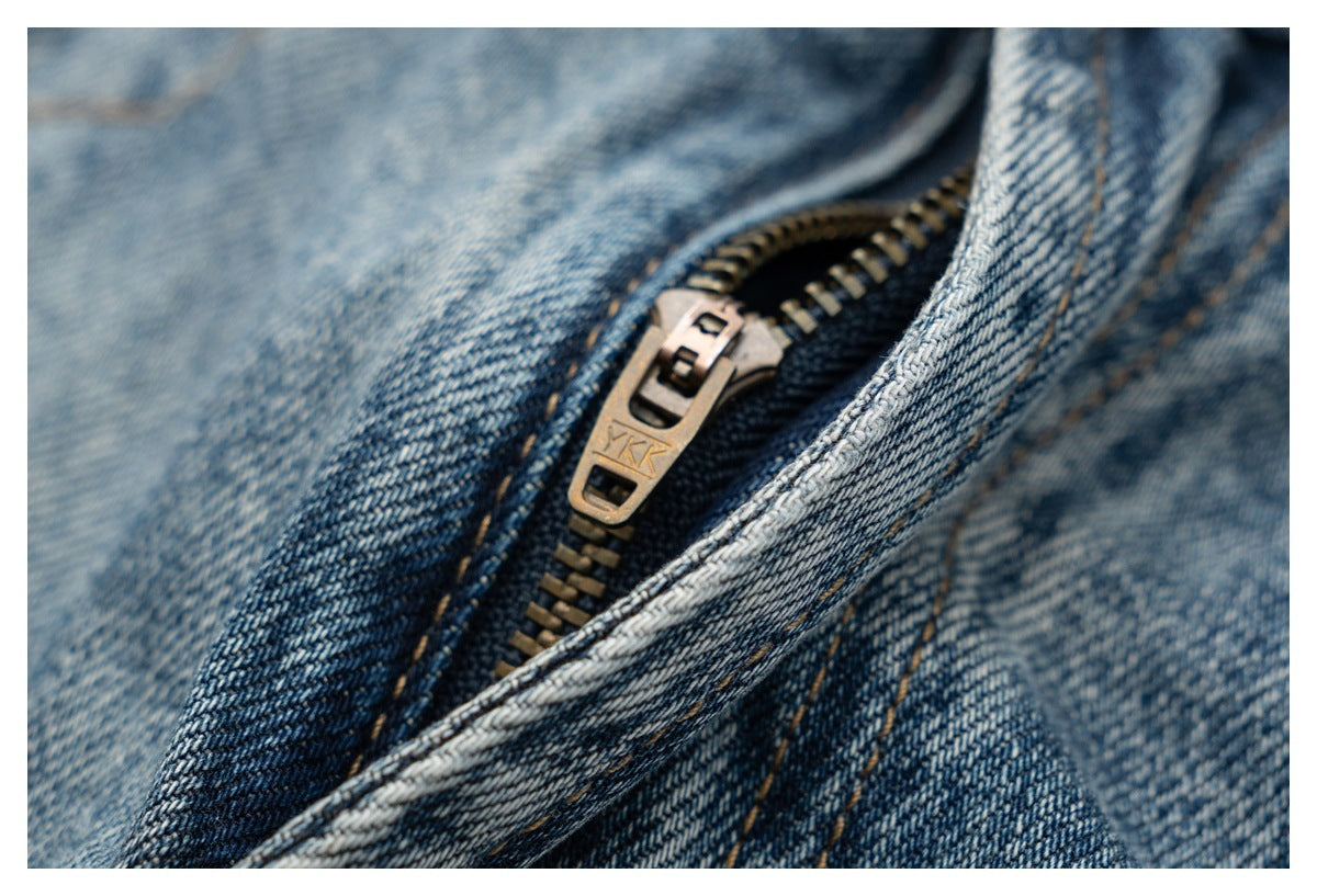 Close-up of a metal zipper and pull on blue denim.