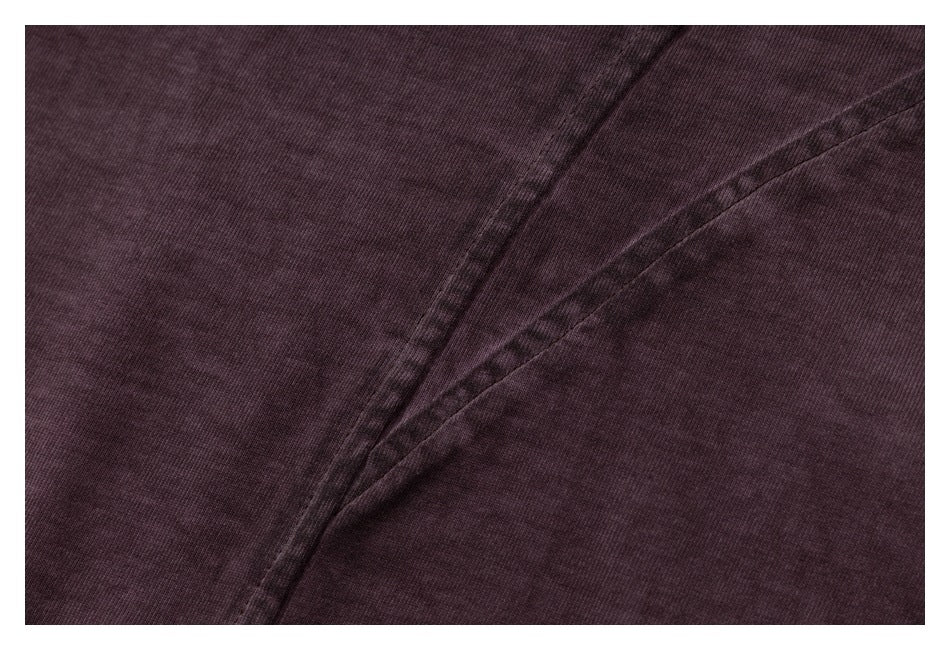 Close-up of intersecting stitched seams on dark plum shirt fabric.