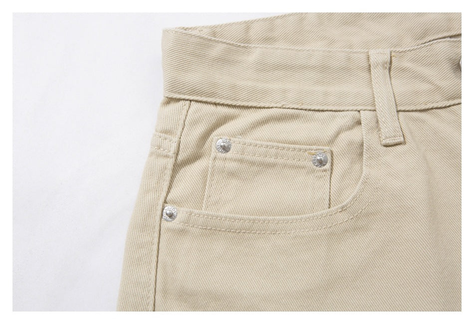 Close-up of the small coin pocket and rivets on beige pants.