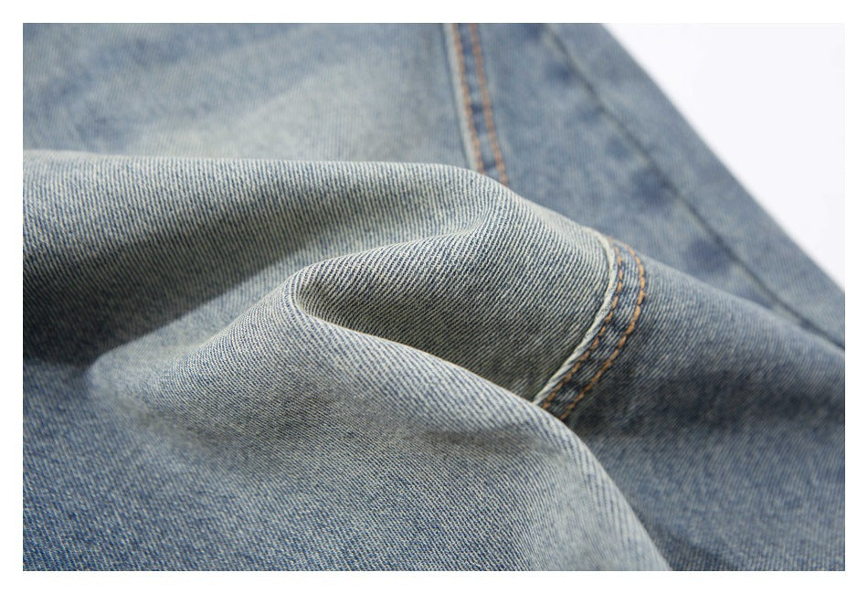 Macro view of folded blue denim with a curved orange-stitched seam.
