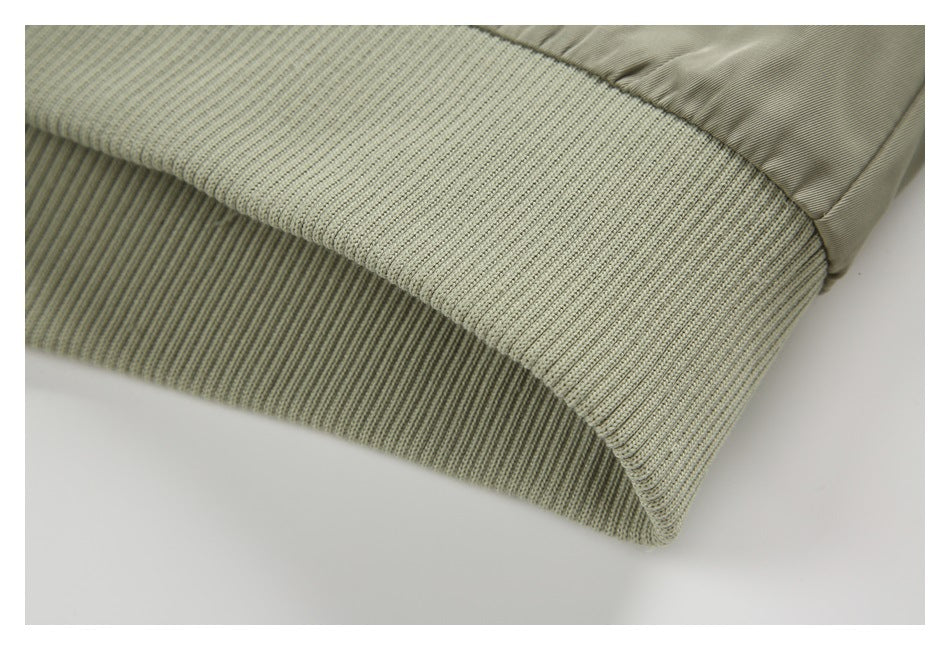 Close-up of the olive jacket’s wide ribbed knit waistband and gathered shell fabric.