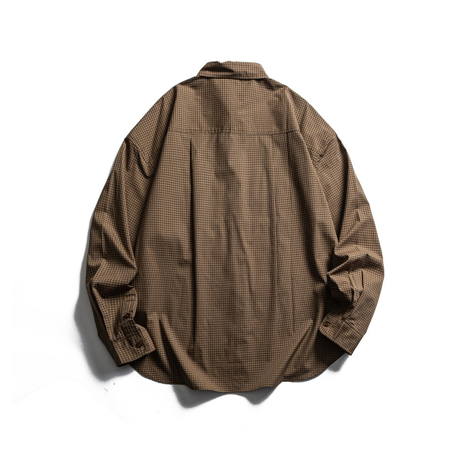 Back of a brown checked button-up shirt laid flat, showing the yoke seam and center pleat.