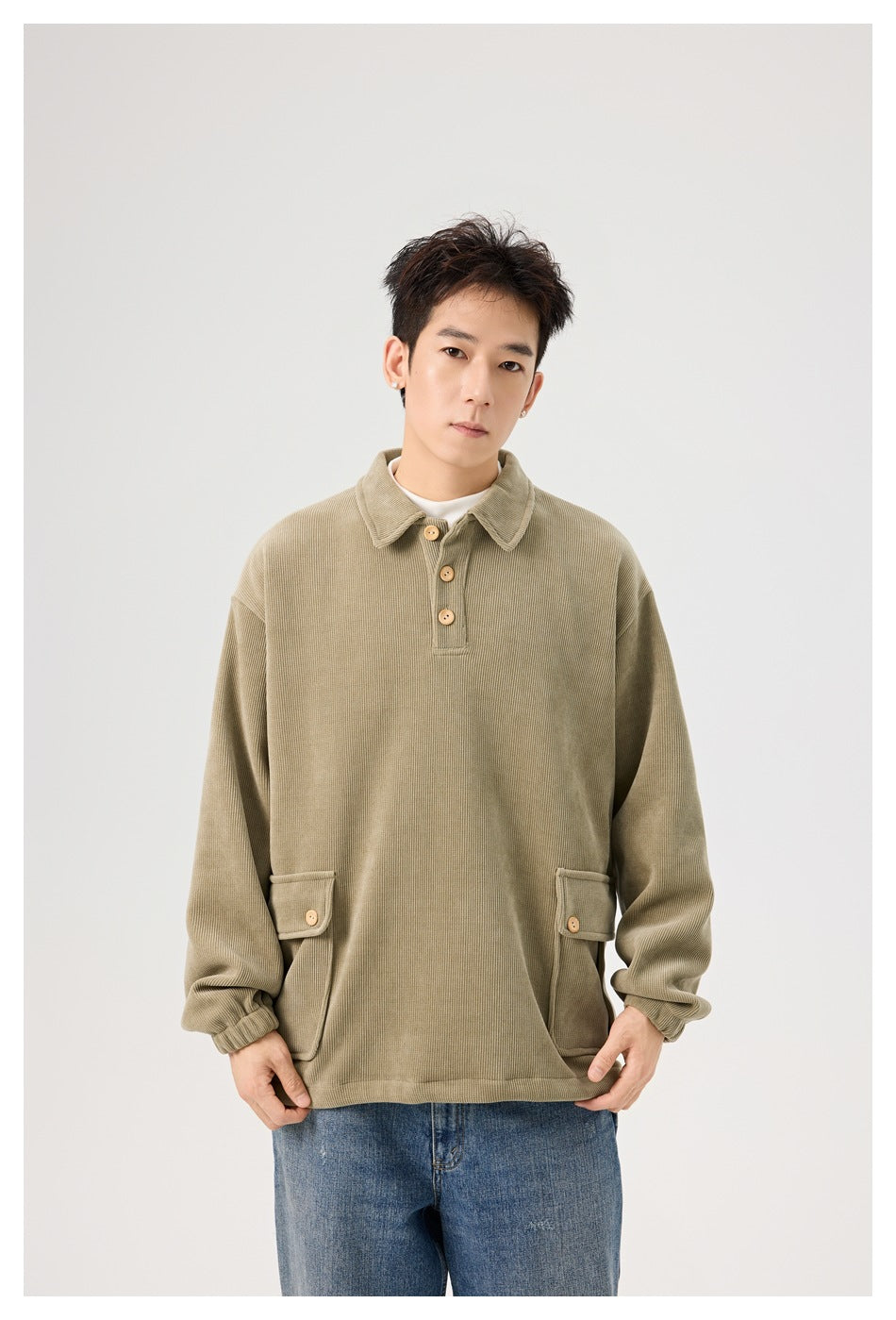 Model wearing a loose olive-beige collared pullover with a three-button placket and flap pockets.