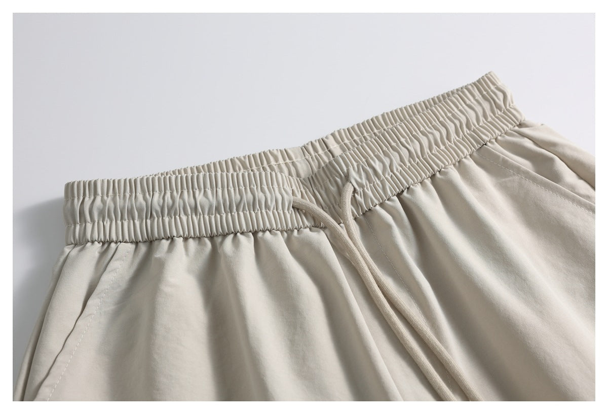 Close-up of light beige shorts with a gathered elastic waistband and matching drawstring.