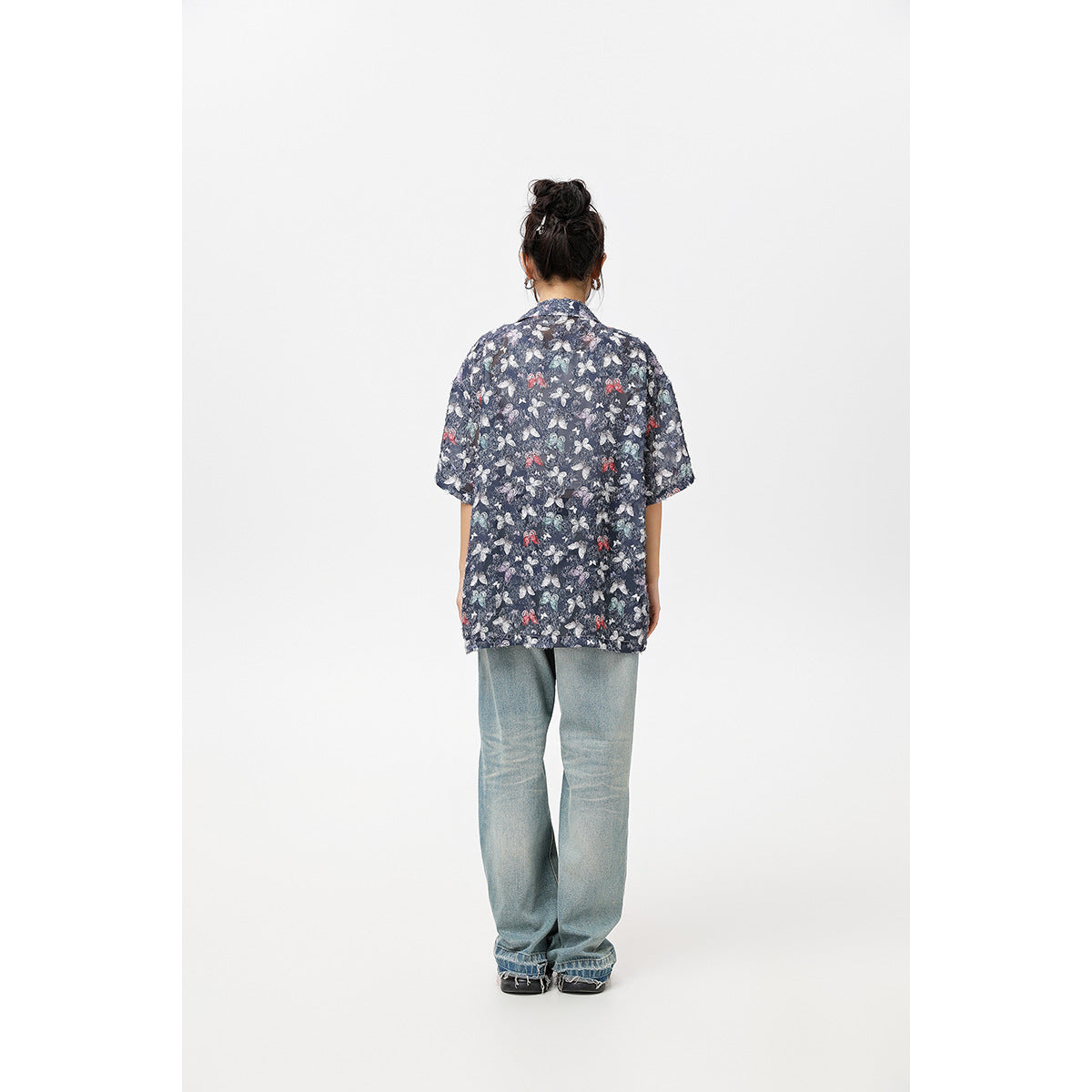 Back view of a model wearing an oversized navy short-sleeve shirt with a multicolor butterfly print.