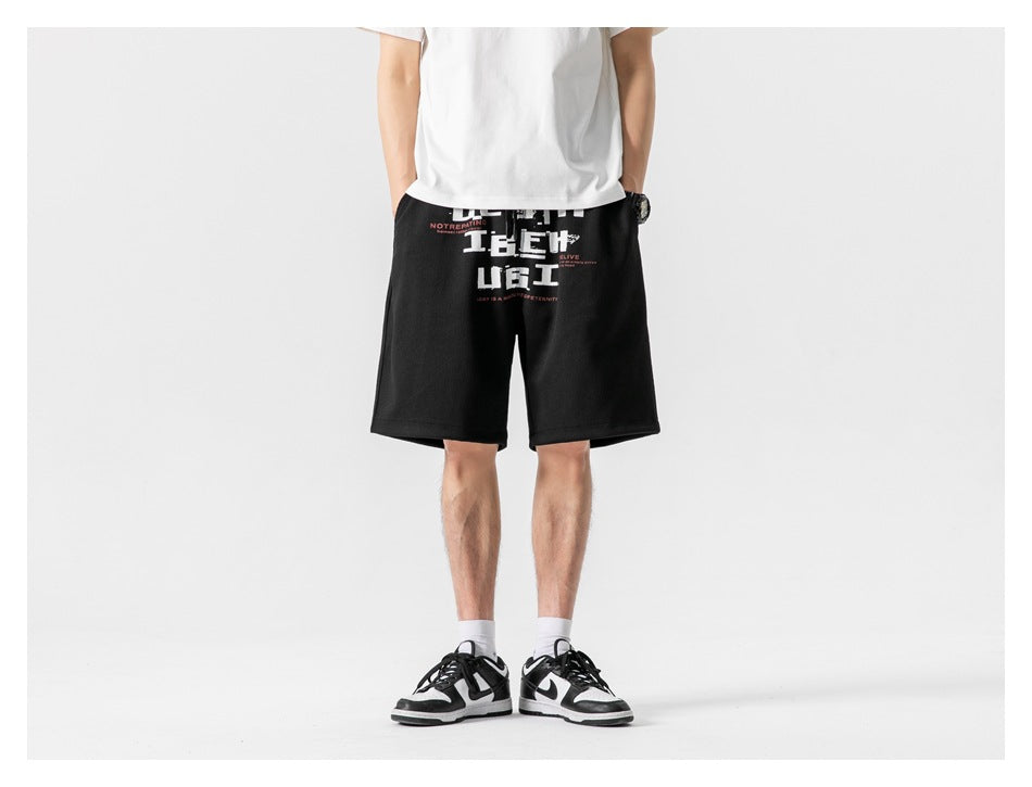 Front view of a model wearing black knee-length shorts with a large white and red graphic print.