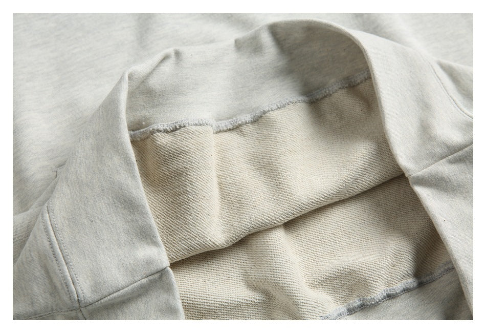 Close-up of the light gray sweatshirt interior, showing soft looped fabric and overlock stitching.