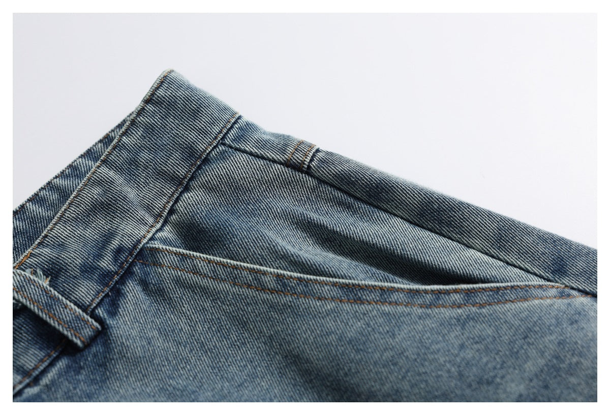 Close-up of washed blue jeans showing a belt loop, waistband seam, and angled stitched panel.
