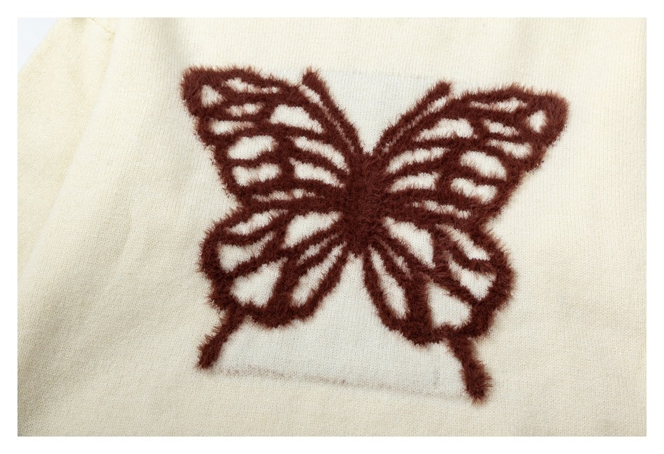 Close-up of a dark brown butterfly motif on a cream knit sweater.