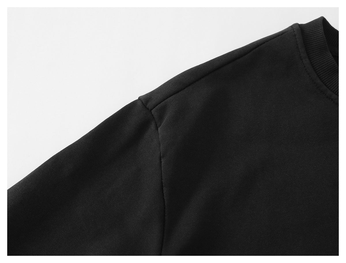 Close-up of a black sweatshirt's shoulder seam, sleeve, and ribbed neckline.