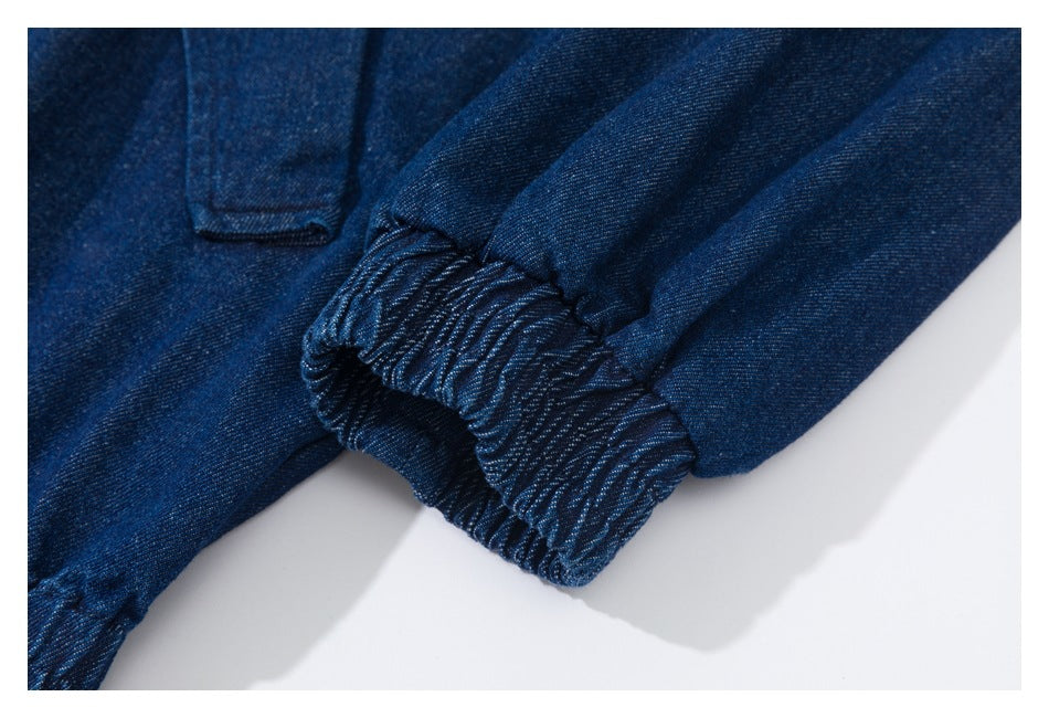Close-up of an elasticized denim cuff beside a narrow tab pocket.