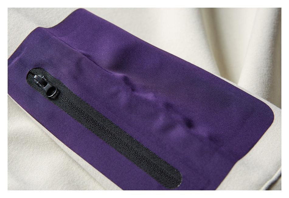 Close-up of a purple rectangular pocket panel with a black zipper on a pale cream garment.
