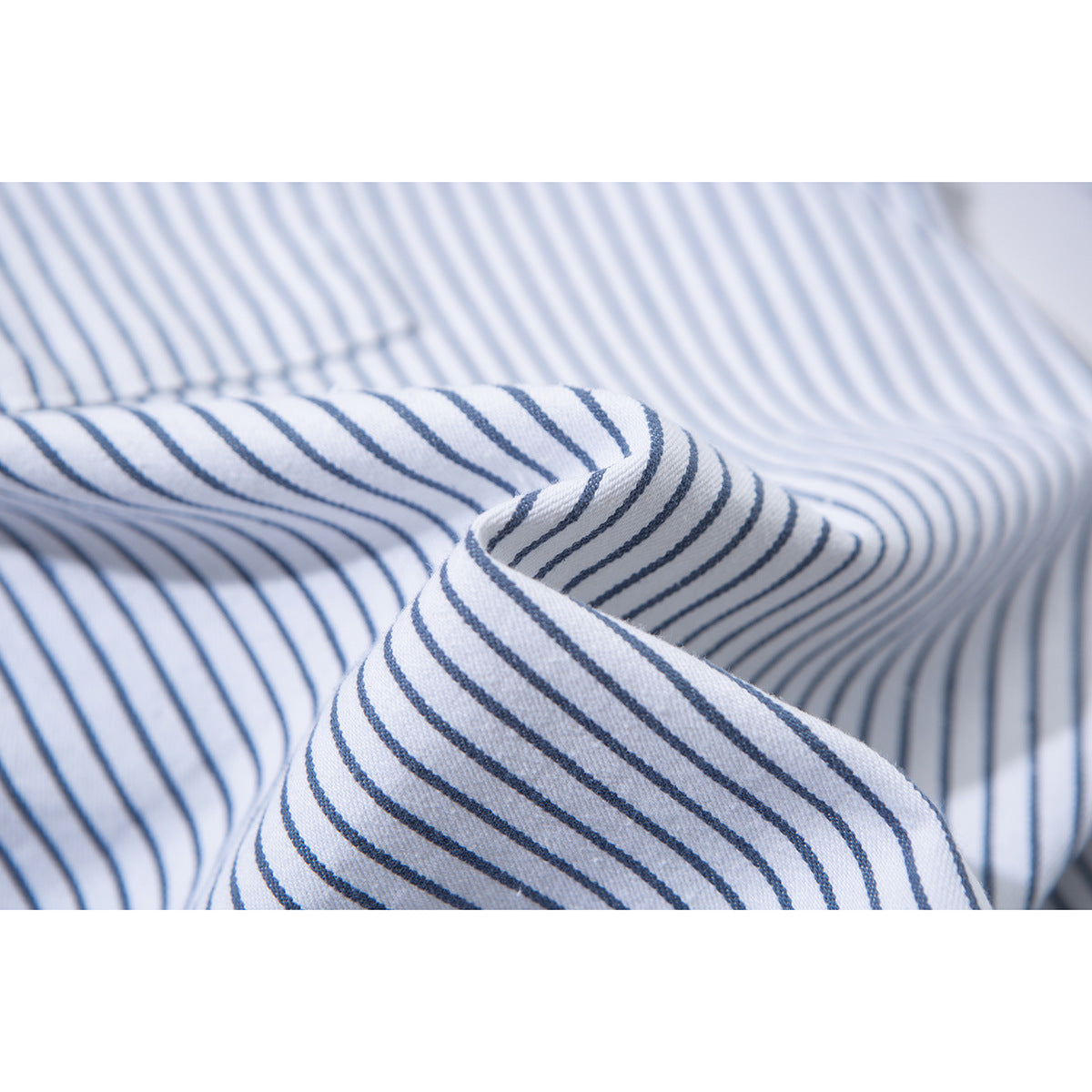 Macro view of white shirt fabric with thin blue stripes and a folded seam.