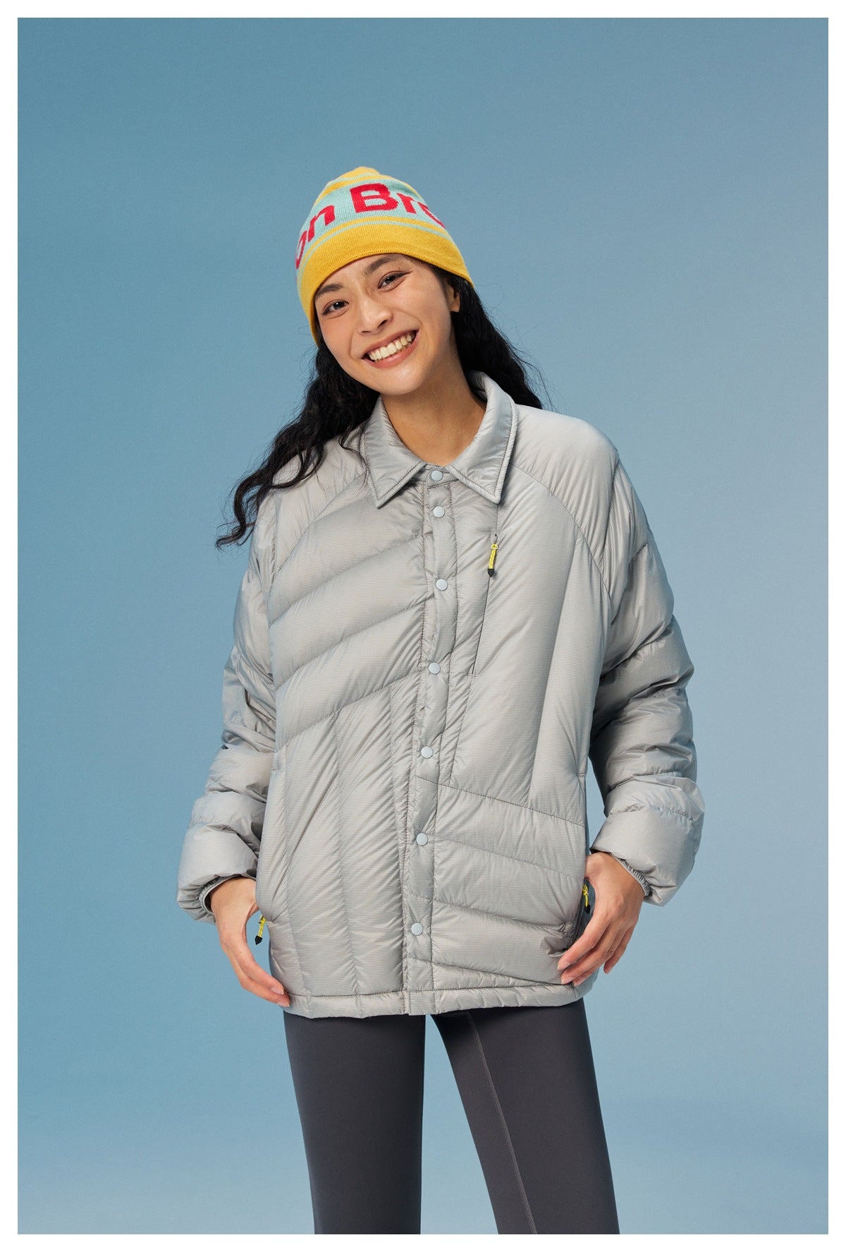 Model wearing a light gray quilted jacket with a pointed collar, snap front, and zip details.