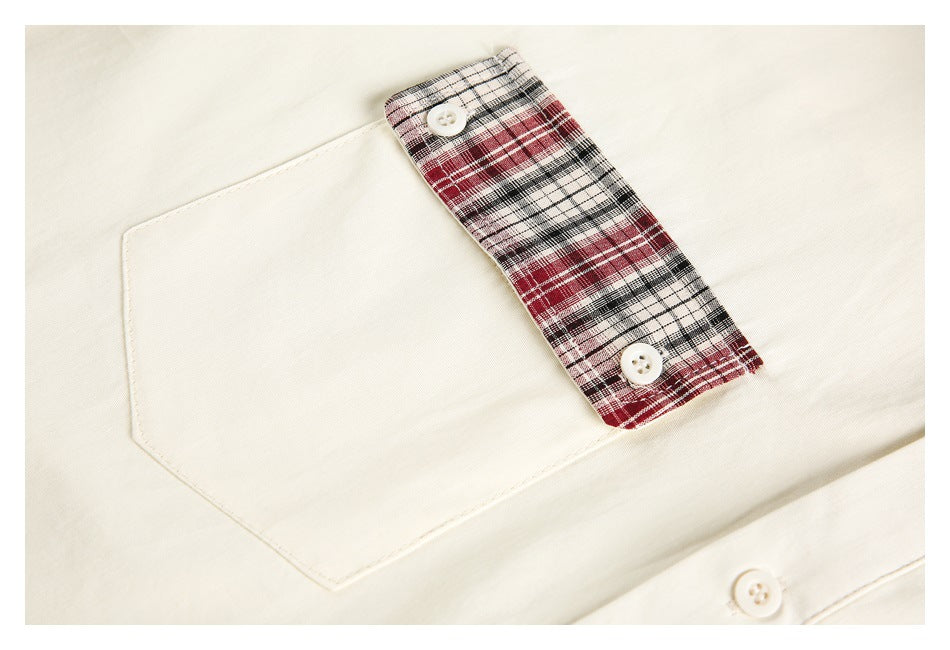 Close-up of an ivory shirt pocket with a red, black and white plaid buttoned flap.