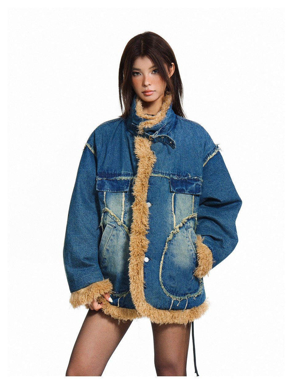 Model wearing an oversized blue denim jacket with tan shaggy trim, patch pockets, and a high buckled collar, front view.