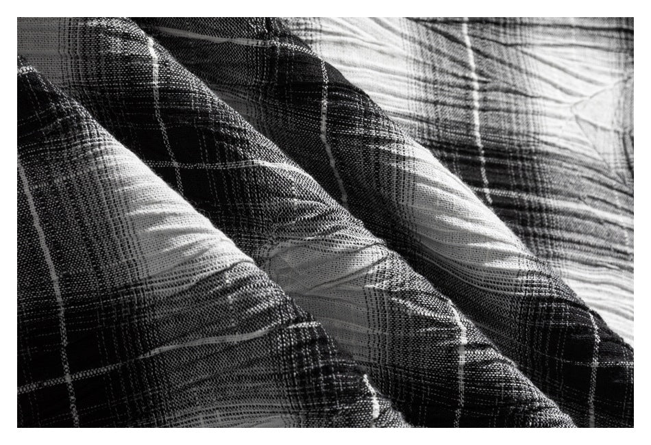 Close-up of folds in the black-and-white plaid fabric, highlighting its woven texture.