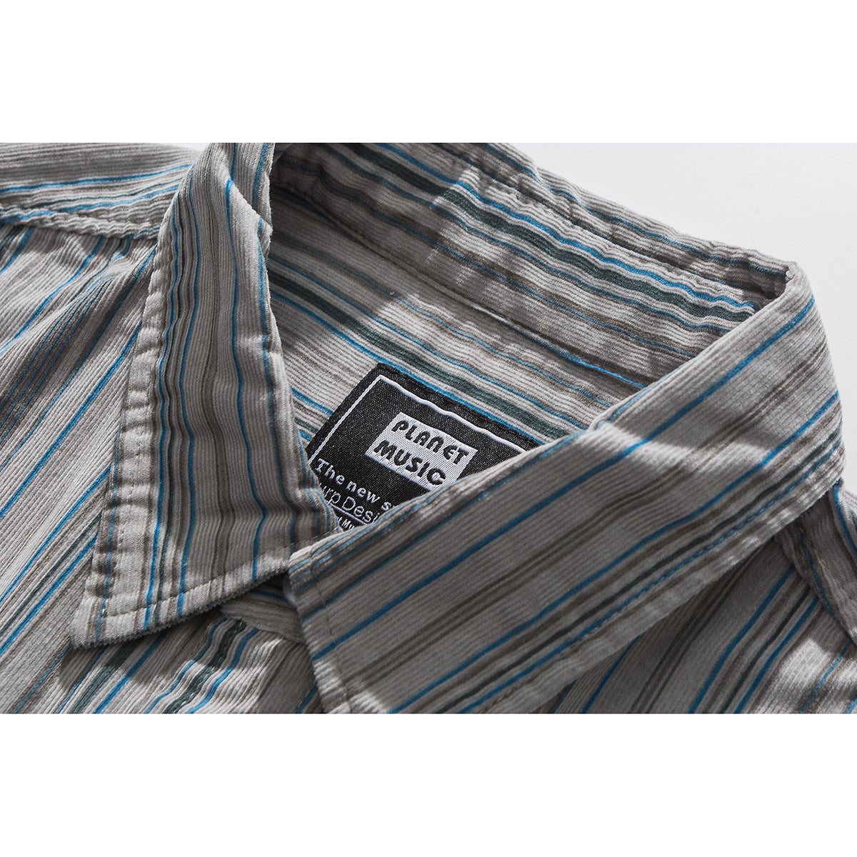 Close-up of a gray striped shirt collar with thin blue lines and a black woven neck label.