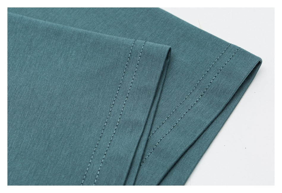 Close-up of the teal garment's folded hem and parallel rows of stitching.