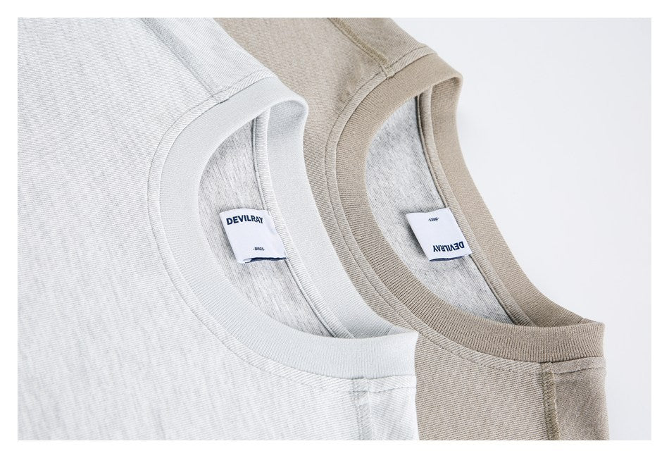 Close-up of light gray and beige crew necklines, showing ribbed collars, seams, and interior labels.