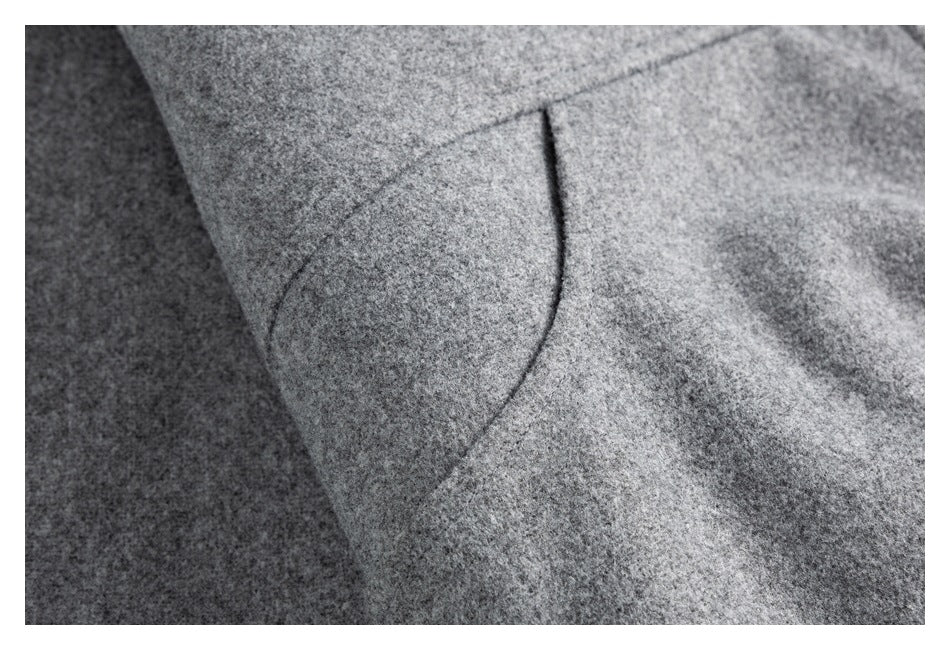 Close-up of a curved pocket opening on the gray coat.
