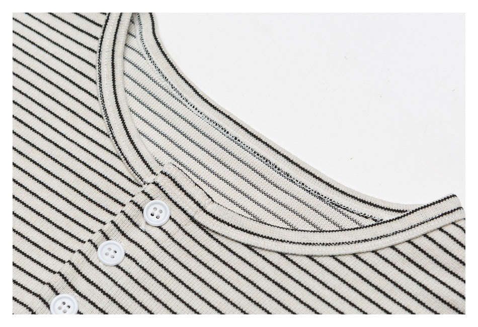 Close-up of the cream shirt’s striped crew neckline and white buttons on its short front placket.