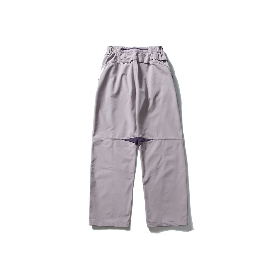 Back view of loose pale lavender-gray pants with an elastic waist and dark purple gusset accent.