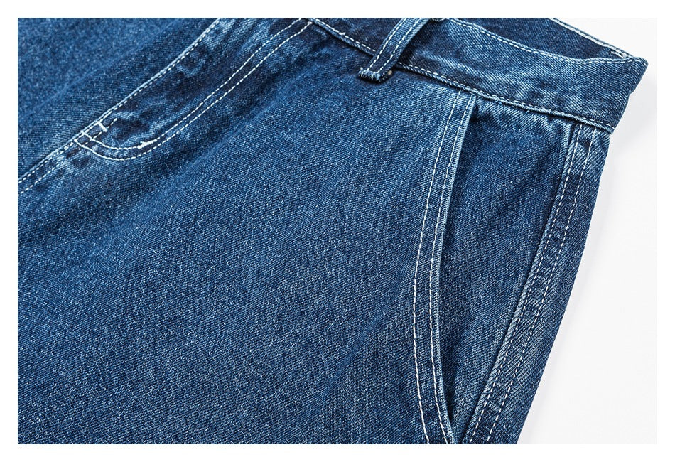 Close-up of blue denim shorts showing a curved front pocket, waistband, belt loop, and side seam.